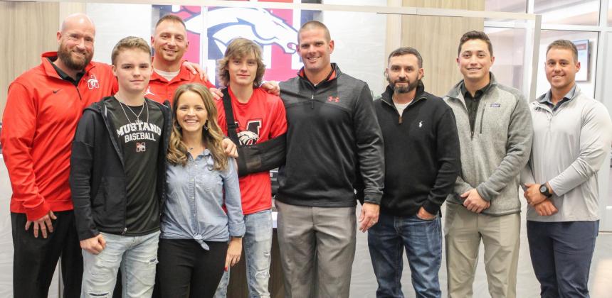 Mustang High School coaches stand for a photo with the Doyle family at Monday’s Mustang Public Schools’ Board of Education meeting. The coaches — Aron Miller, Joe Patterson, Joe Moore, Pat Kenedy and Hunter Aguirre — saved senior Connor Doyle’s (pictured in middle with arm sling) life after he went into cardiac arrest Nov. 29. Photo / Haley Humphrey